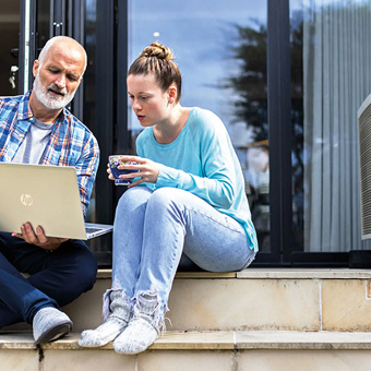 Couple Sitting On Steps Looking At A Laptop Computer